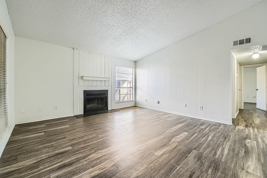 A spacious room with wood flooring and a fireplace.