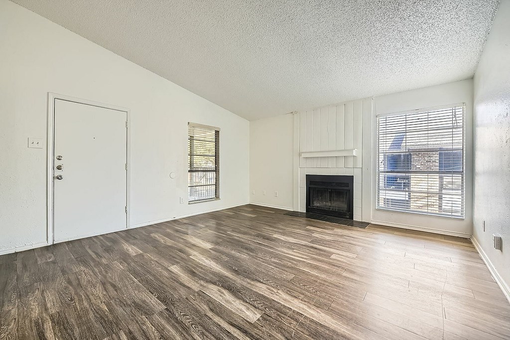A room with a fireplace and wood flooring.