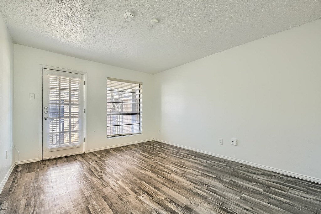 A room with wooden floors and two windows.