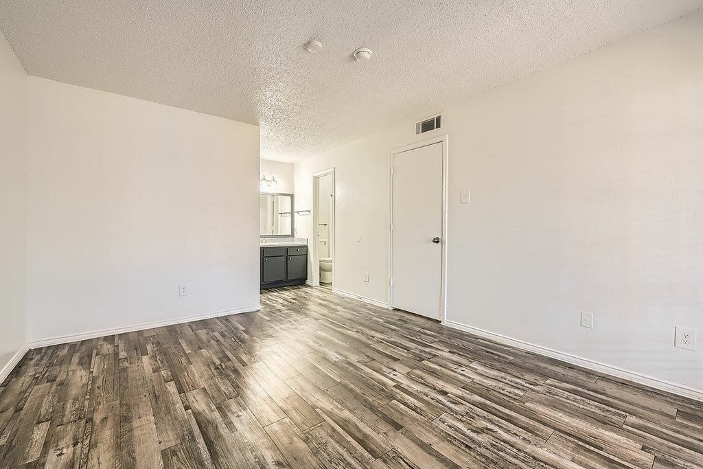 A room with wooden flooring and white walls.