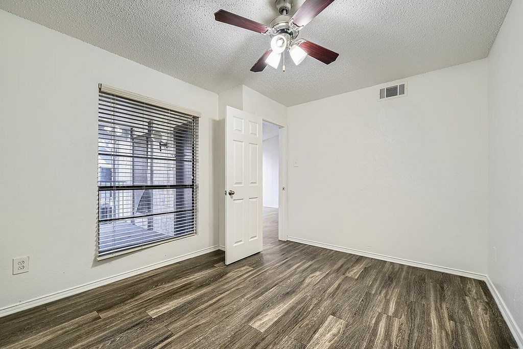 A room with a ceiling fan and a window with blinds.