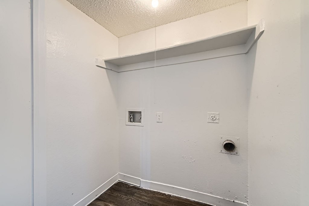 A white wall with a shelf and electrical outlets.