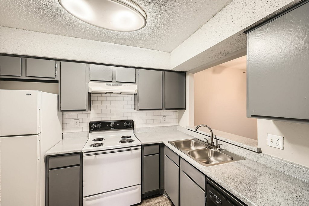 A kitchen with a white fridge, black and white stove, and black dishwasher.