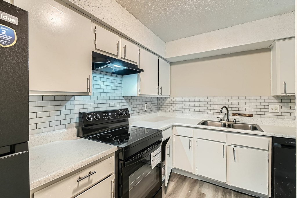 A kitchen with black appliances and white cabinets.