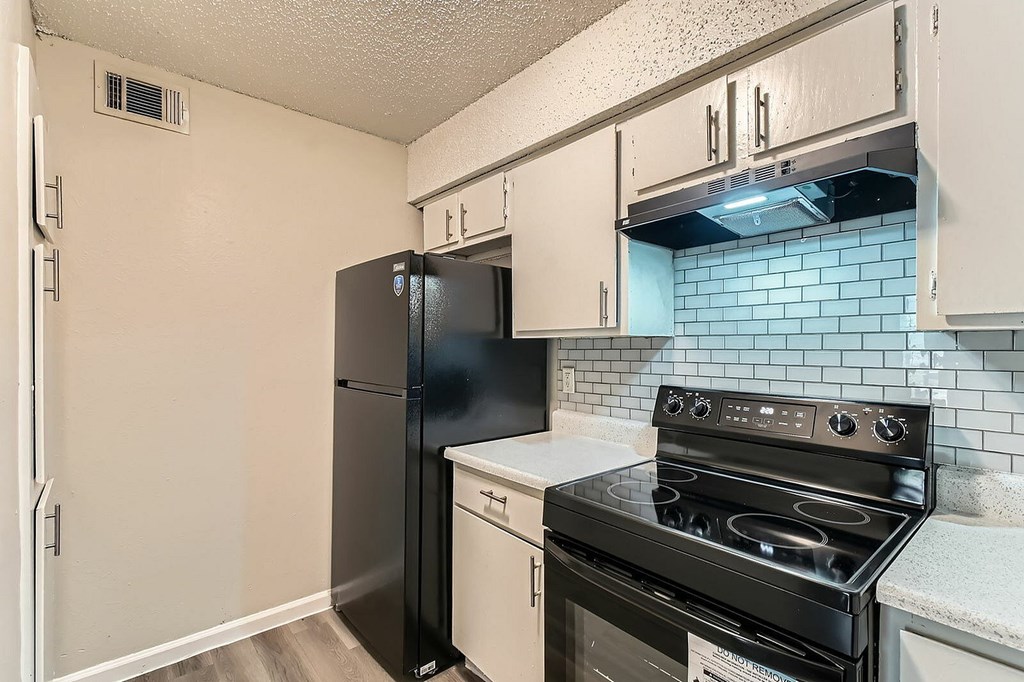 A kitchen with black appliances and white cabinets.