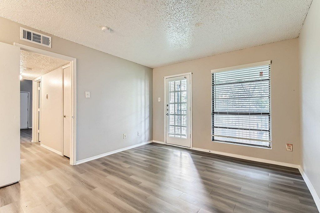 A room with a sliding glass door and a window with blinds.