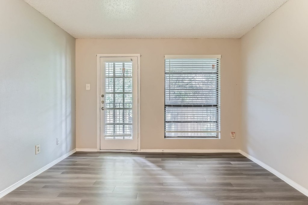 A room with a wooden floor and a white door with a window above it.