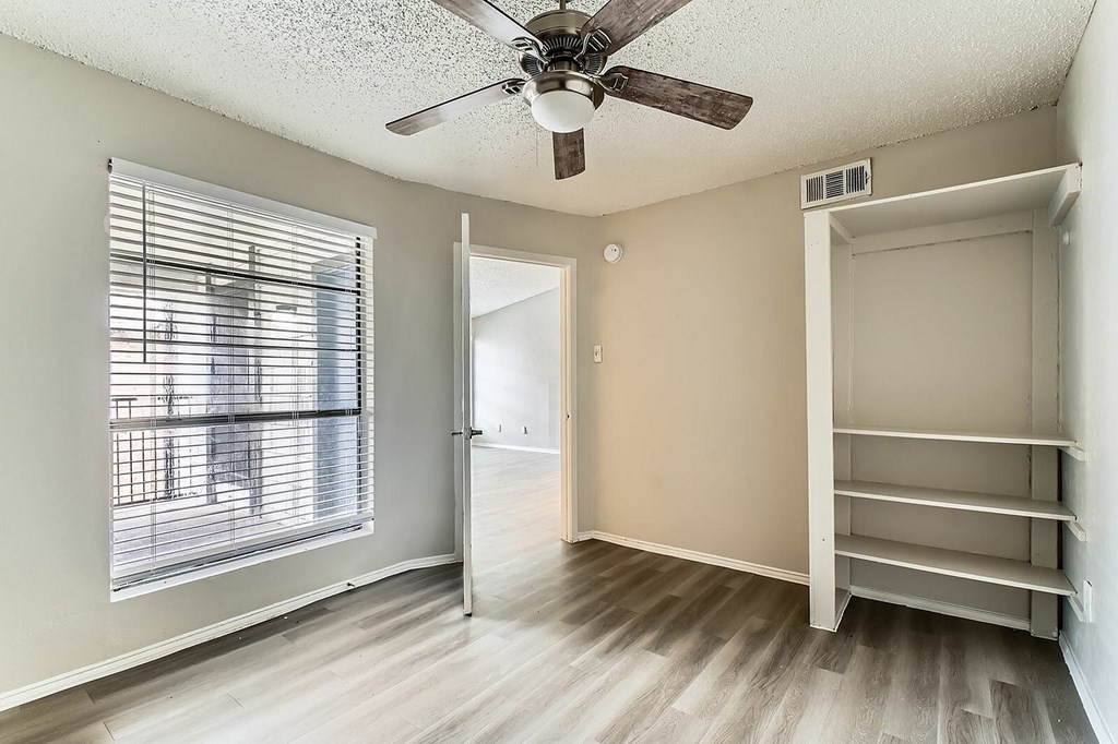 A room with a ceiling fan and a window with blinds.