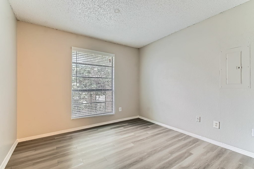 A room with a window and wooden flooring.