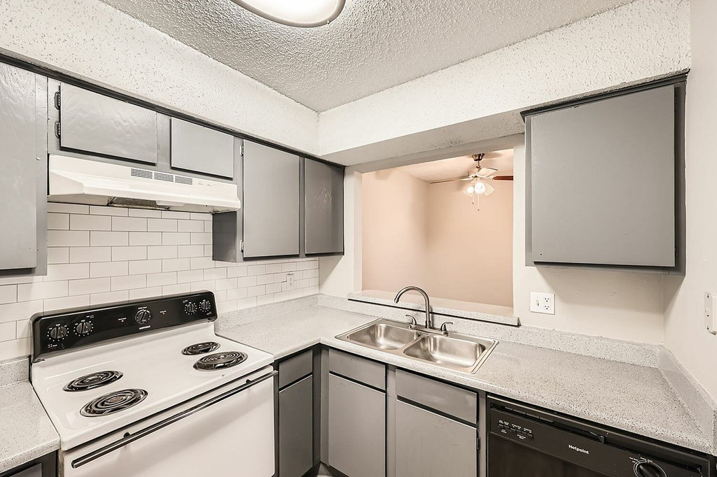 A kitchen with a white stove top oven and a black dishwasher.