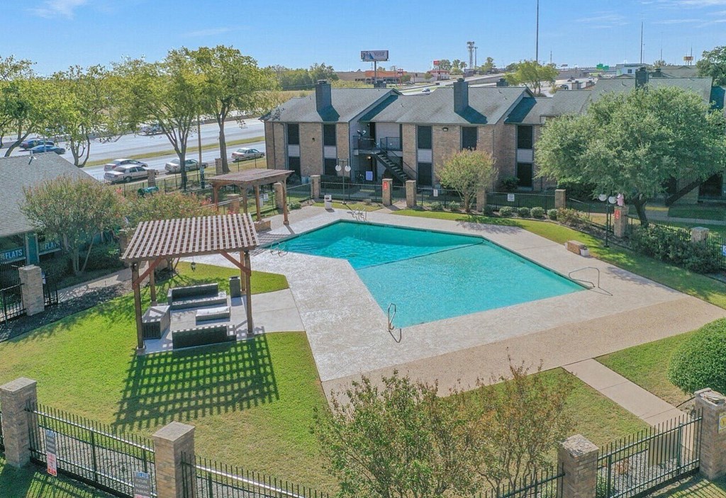 A pool surrounded by a black fence and a gazebo.