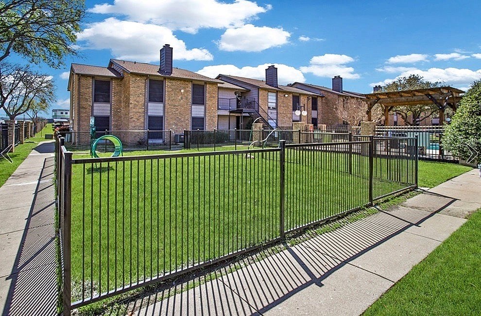 A black metal fence surrounds a green lawn.