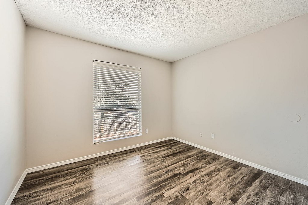 A room with a window and wooden flooring.