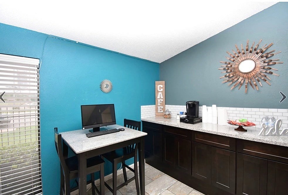 A blue wall with a clock and a sunburst mirror.