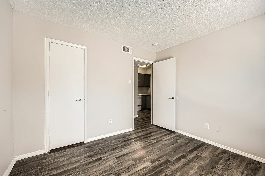 A room with a white door and a brown floor.
