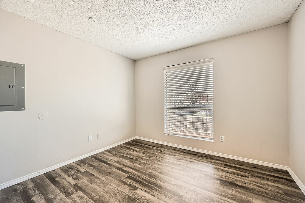 A room with a window covered by blinds and a wooden floor.