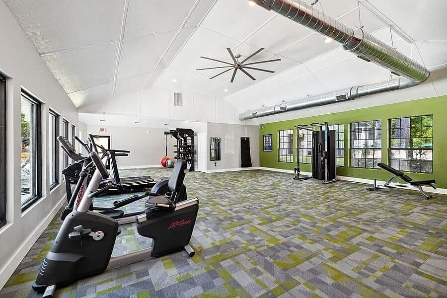 A gym with a variety of equipment including treadmills, weights, and a bench press.