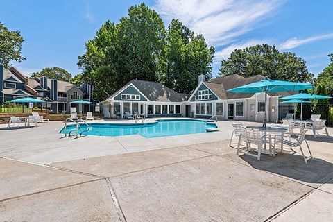 A large outdoor swimming pool with a patio and lounge chairs.