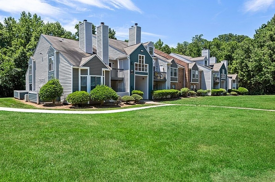 A row of houses with green lawns in front.