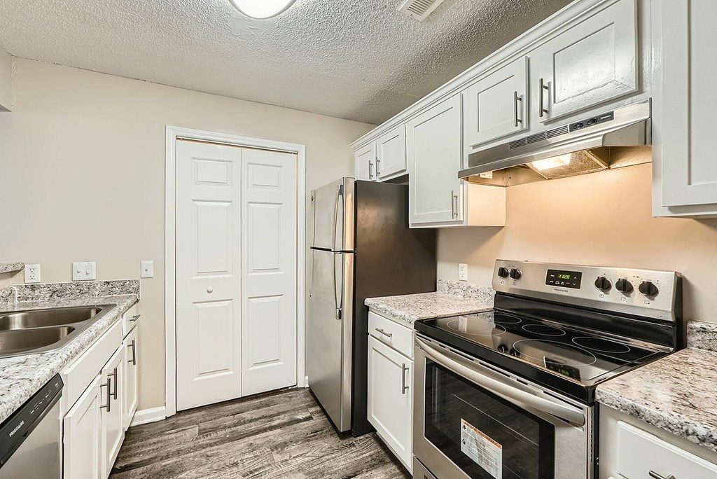 A kitchen with a stove, refrigerator, and sink.