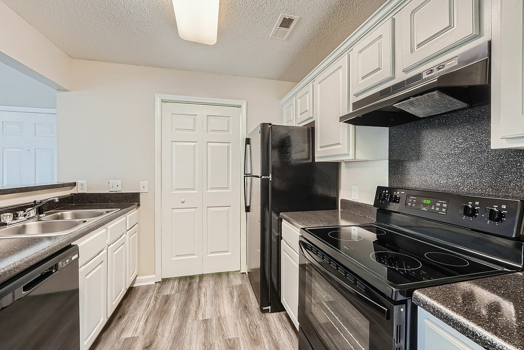 A kitchen with black appliances and white cabinets.