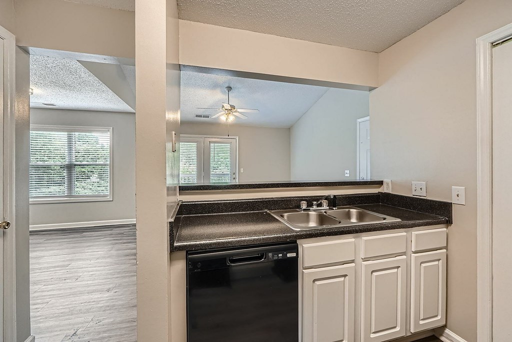 A kitchen with a black dishwasher and white cabinets.