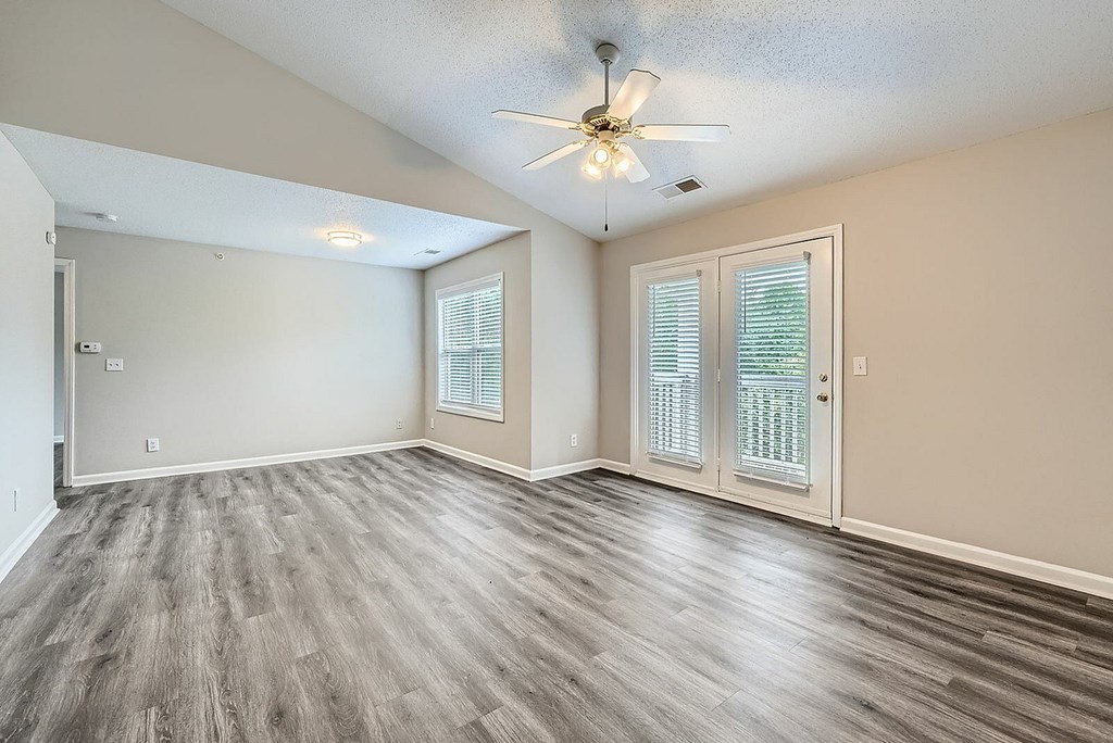 A room with a ceiling fan and sliding glass doors.