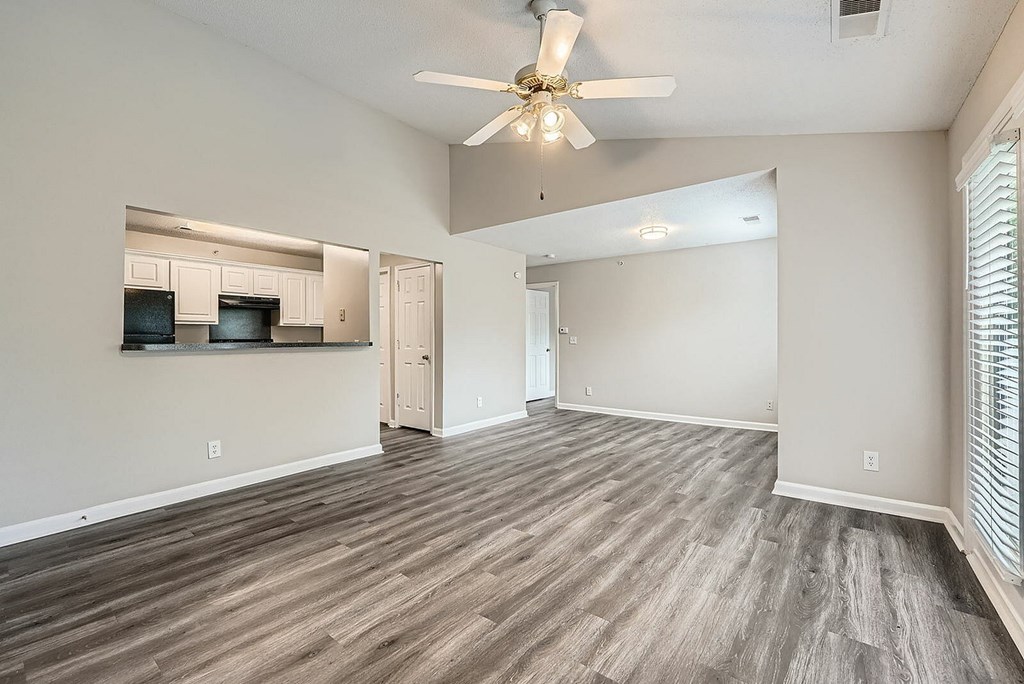 A spacious room with a ceiling fan and lighting fixture.