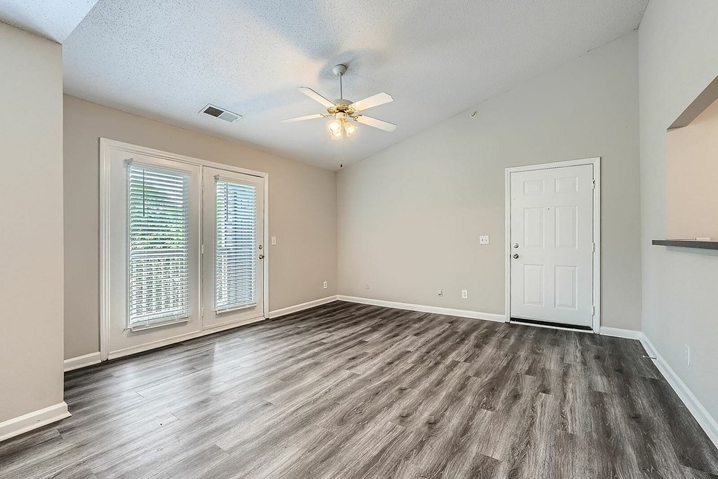 A room with a ceiling fan and sliding glass doors.