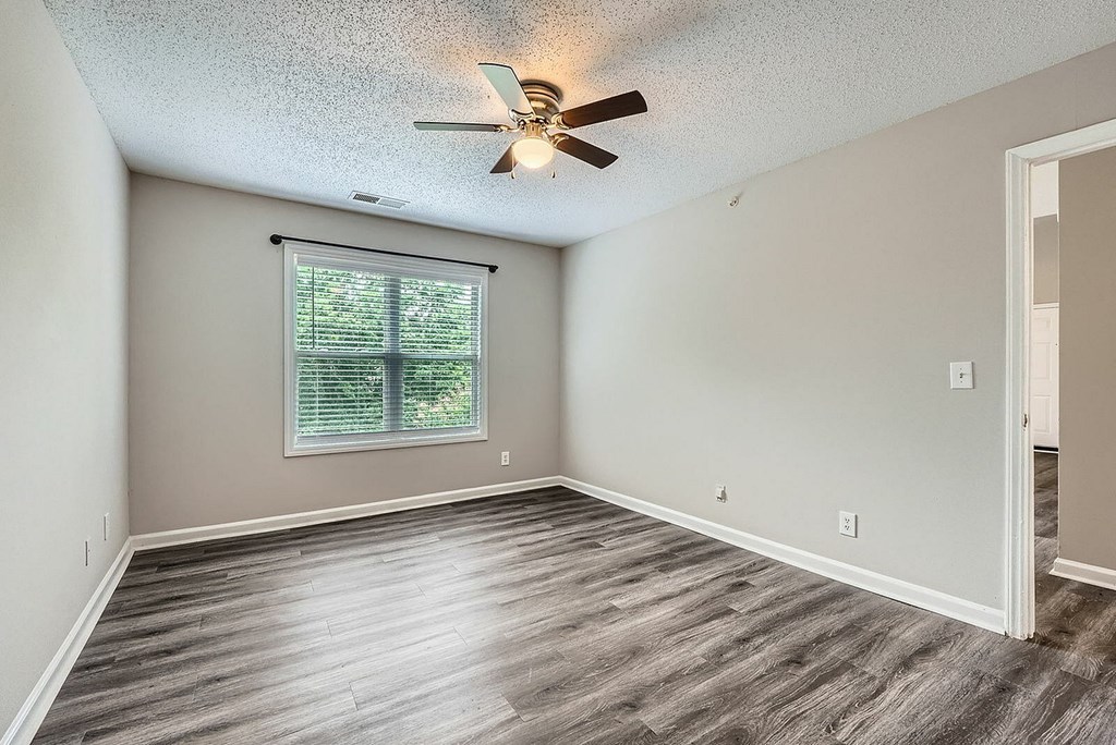 A room with a ceiling fan and a window with blinds.