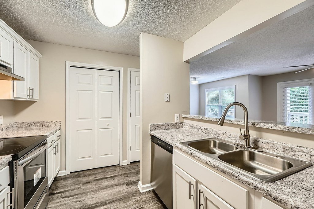A kitchen with a sink, stove, and cabinets.
