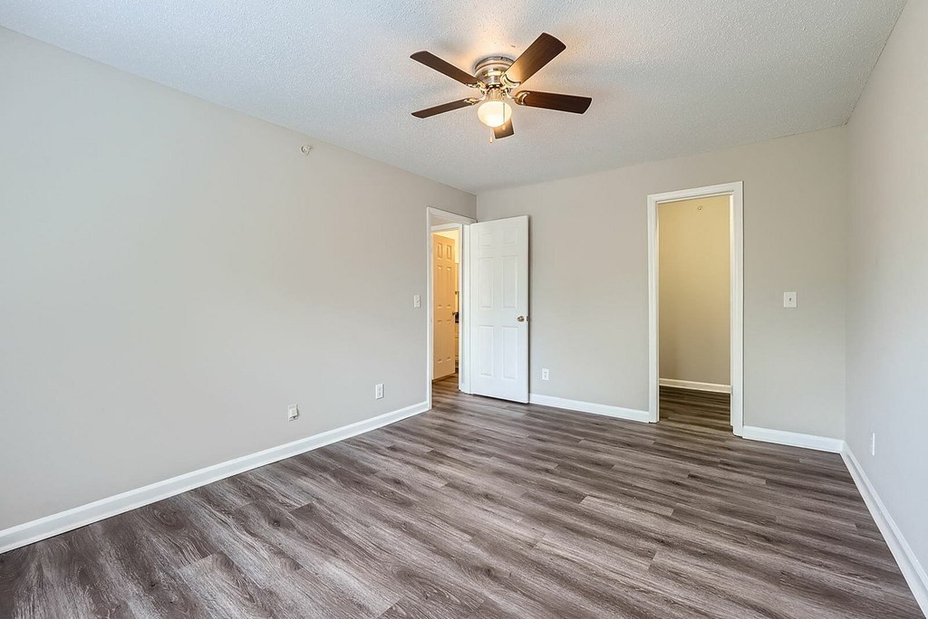 A room with a ceiling fan and wood flooring.