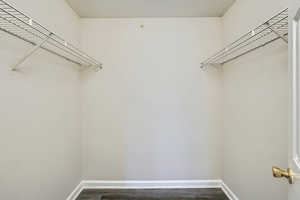 A white closet with a door and a shelf.