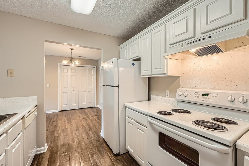 A kitchen with white appliances and wooden floors.