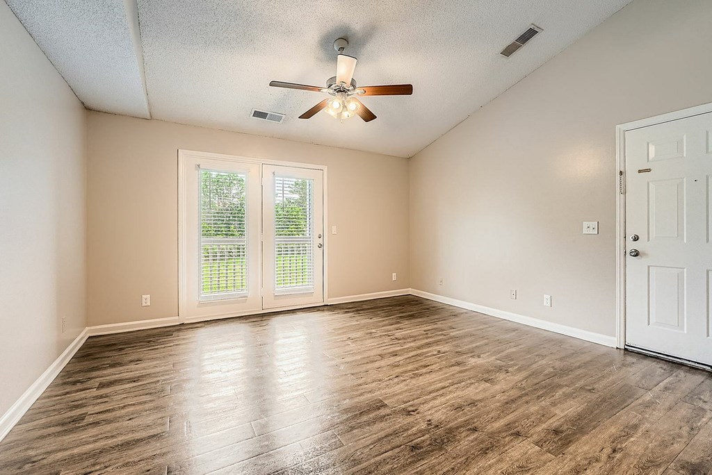 A room with a ceiling fan and sliding glass doors.