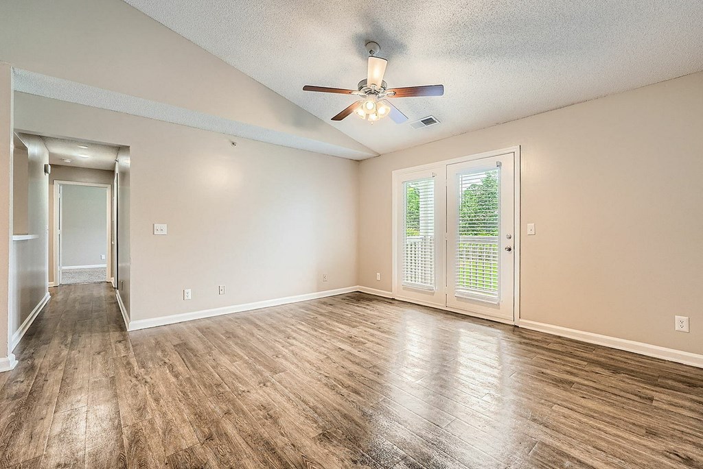 A room with a ceiling fan and wooden flooring.