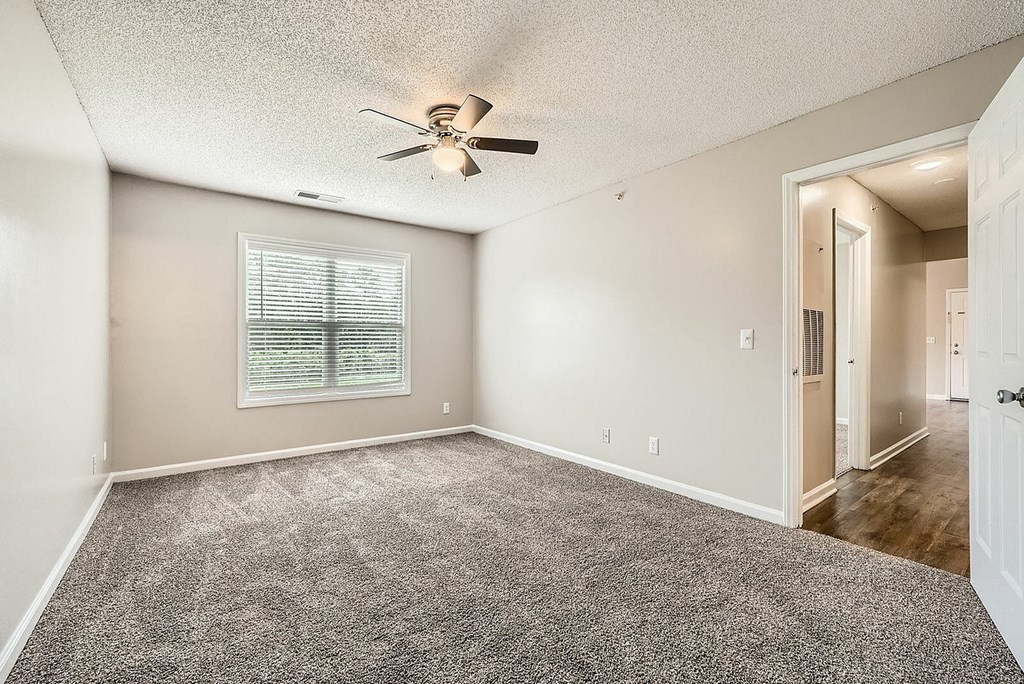 A room with a ceiling fan and a window with blinds.