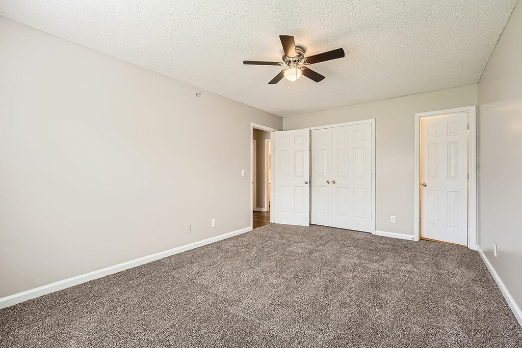 A room with a ceiling fan and carpeted floor.
