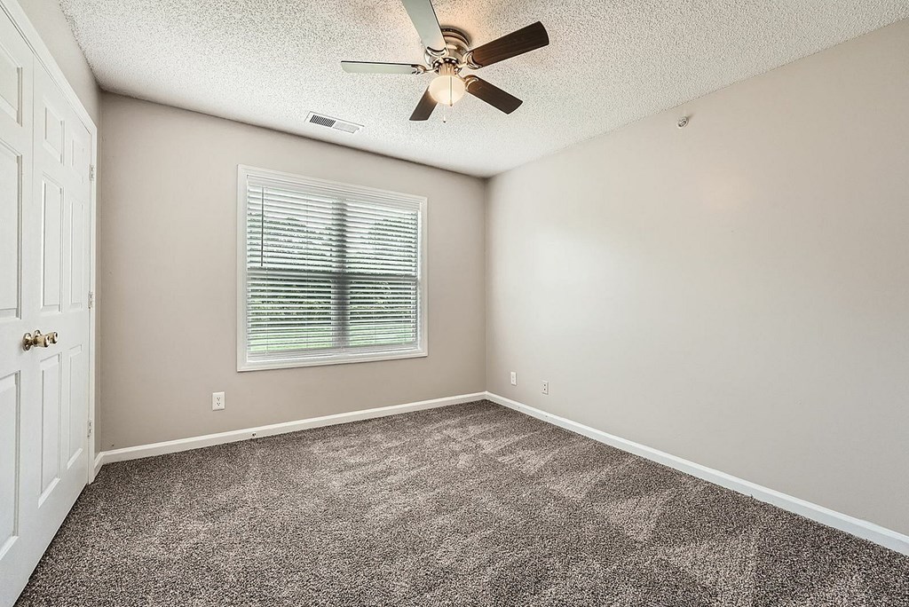 A room with a ceiling fan and a window with blinds.