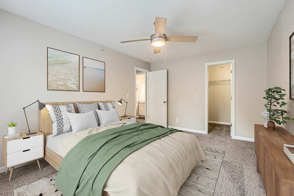 A bedroom with a bed, nightstand, and a ceiling fan.