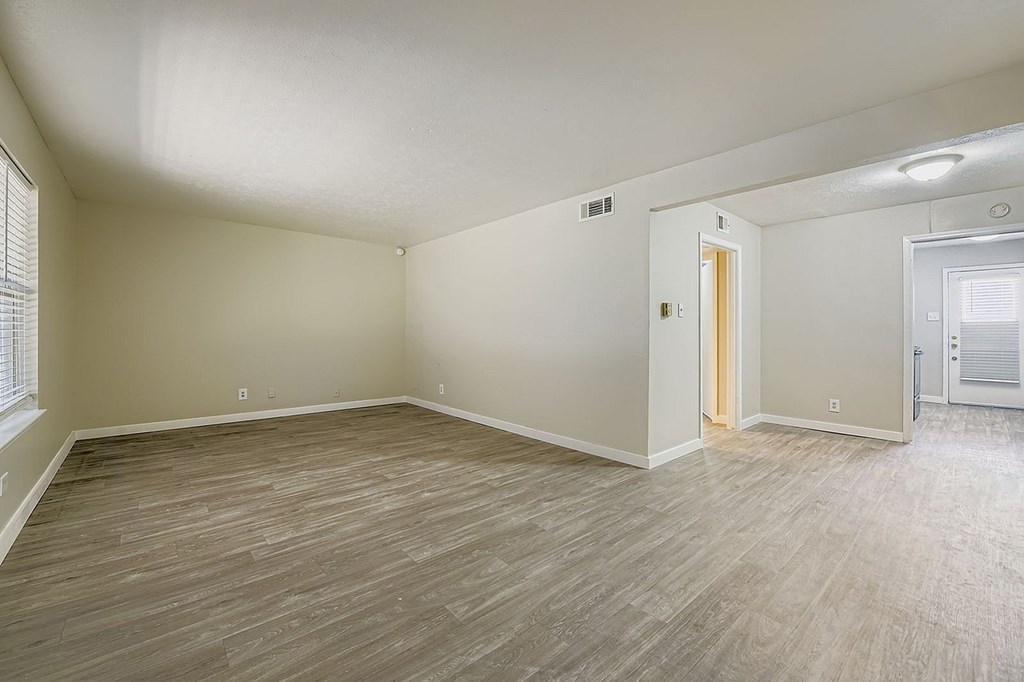 A room with light wood flooring and white walls.