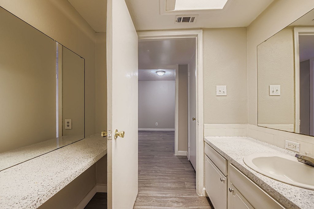 A bathroom with a sink, mirror, and light switches.