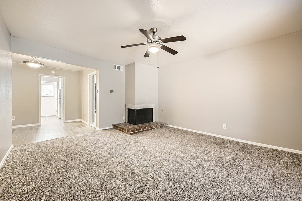 A living room with a fireplace and a ceiling fan.