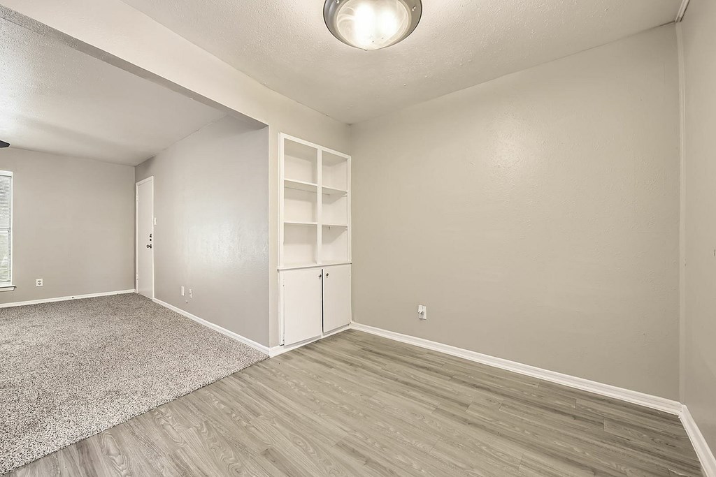 A room with a grey carpet and wooden flooring.
