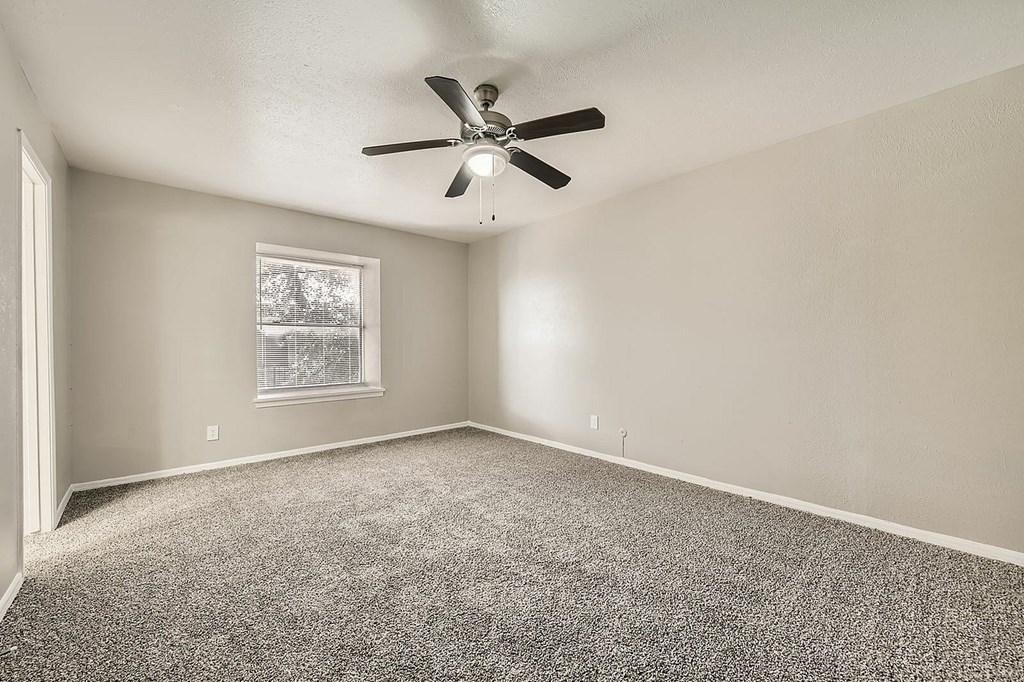 A room with a ceiling fan and carpeted floor.