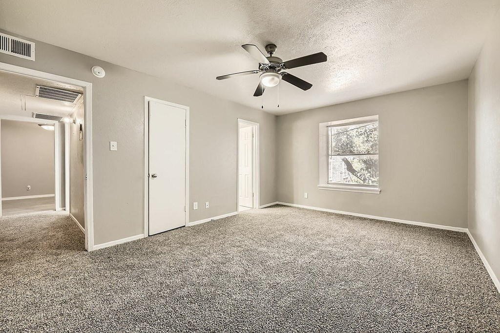 A room with a ceiling fan and carpeted floor.