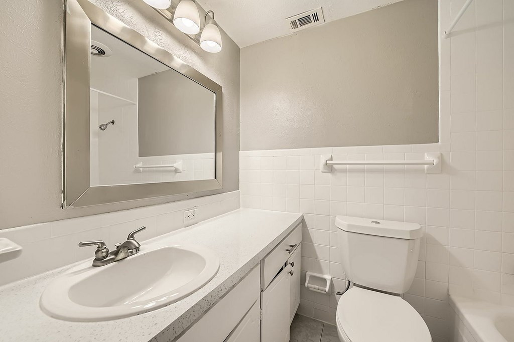 A white bathroom with a sink, toilet, and mirror.