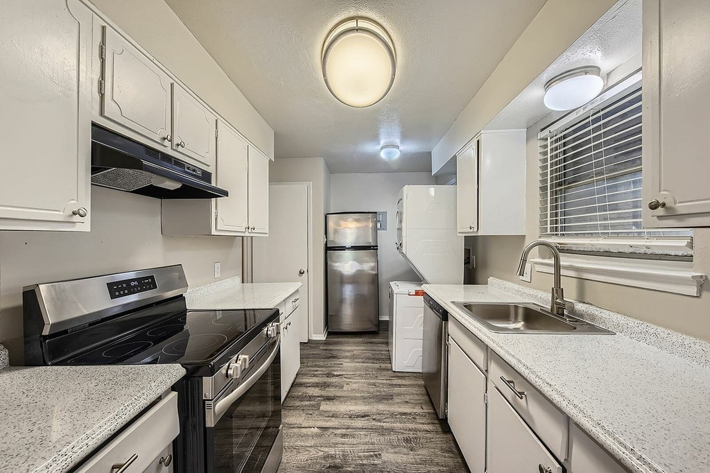 A kitchen with white cabinets and a black counter top.