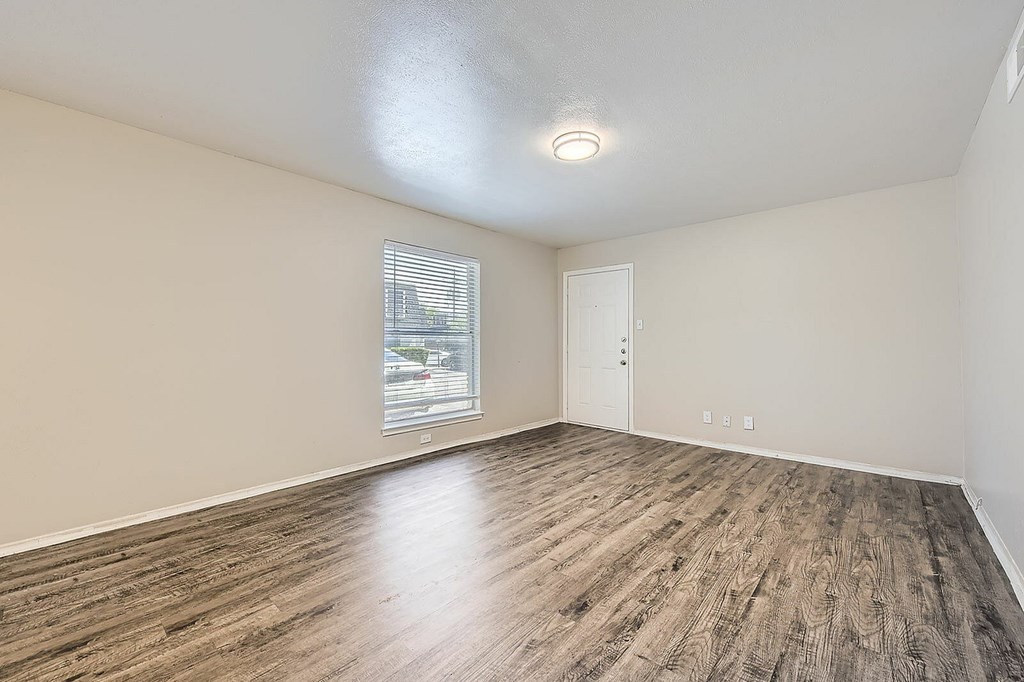 Empty room with wooden flooring and a window.