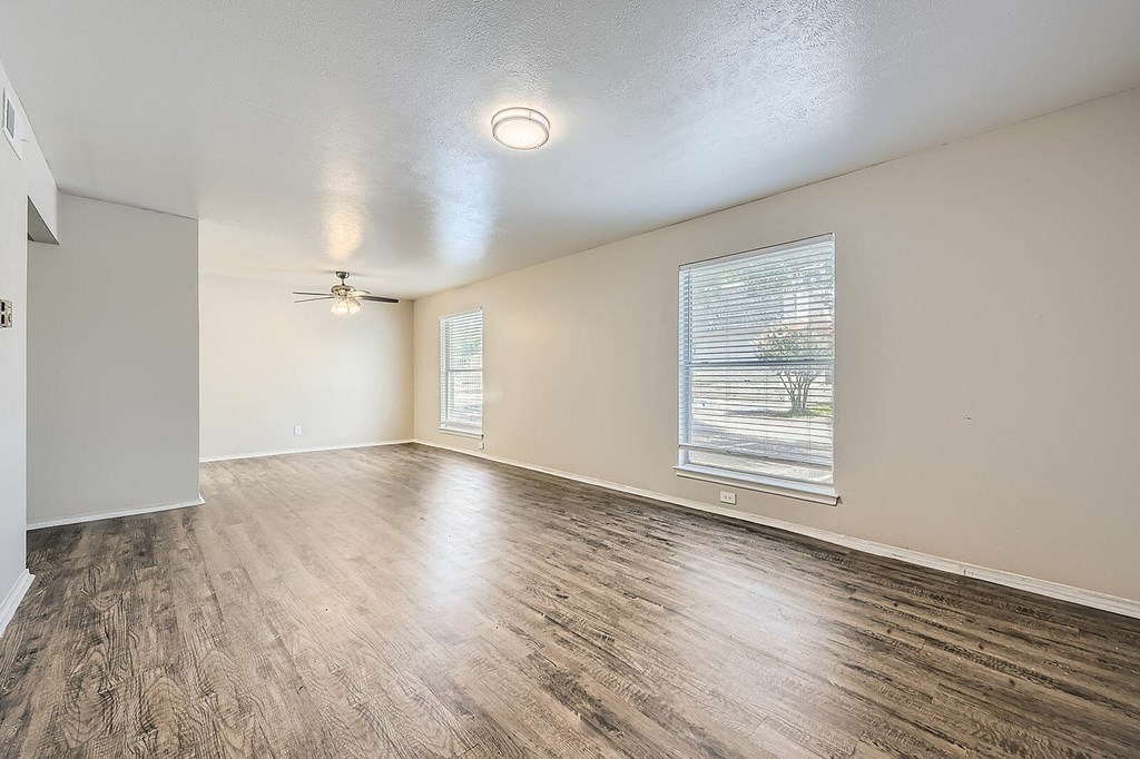 A room with a ceiling fan and a window with blinds.